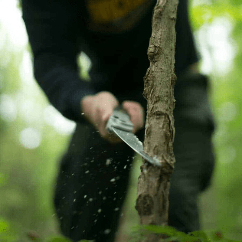 Man cutting sapling with folding hand saw. 